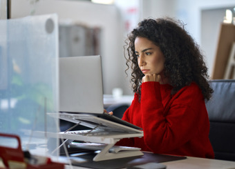 woman at home office looking focused at laptop