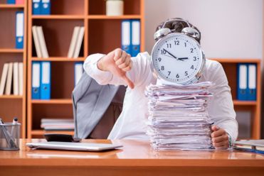 person giving thumbs down with clock on top of paperwork