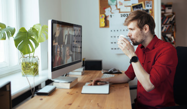 man drinkt koffie tijdens online vergadering