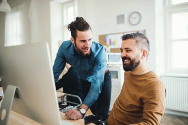 Jeunes hommes travaillant ensemble sur un ordinateur