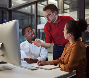 two men and a woman working late by computer