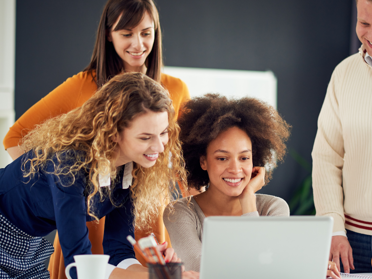 Group of people smiling gathered around a laptop