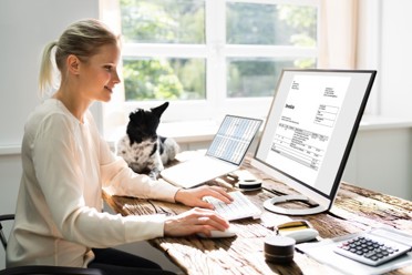 woman at home sitting at a desk smiling at a computer